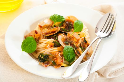 A white plate with delicious spaghetti shellfish and green basil.