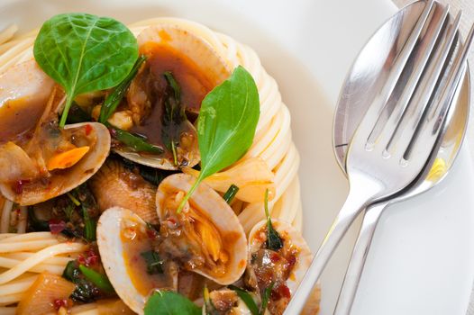 A white plate with delicious spaghetti shellfish and green basil.