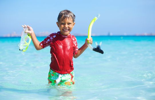 Portrait of happy cute boy with snorkeling mask ready to dive in the sea