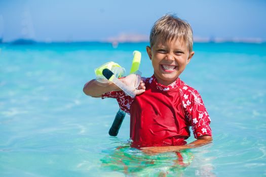 Portrait of happy cute boy with snorkeling mask ready to dive in the sea