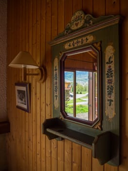 Reflections of outside in a classic antique mirror inside a wooden chalet