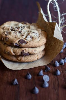 Fresh chocolate chunk cookies wrapped in paper and tied up with twine and sitting on a wooden counter.