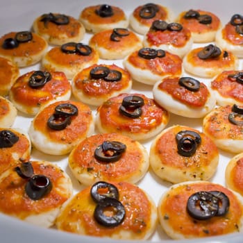 round meat pies with topping black olive sliced on buffet line