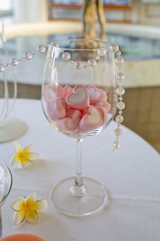 decoration of wedding table. candy of heart shape in wine glass.