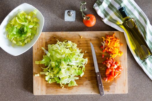 High Angle View of Fresh Healthy Chopped Vegetables on Top of Wooden Cutting Board with Knife for Healthy Salad