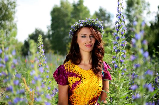 Beautiful girl from Poland with wreath made of flowers. Portrait of female model surrounded by heathers.