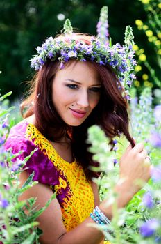Beautiful girl from Poland with wreath made of flowers. Portrait of female model surrounded by heathers.