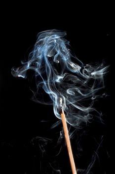 Braised match with smoke swirling on a black background