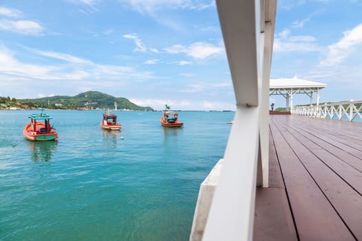 wooden bridge that stretches to the sea. A fishing boat moored near the bridge.