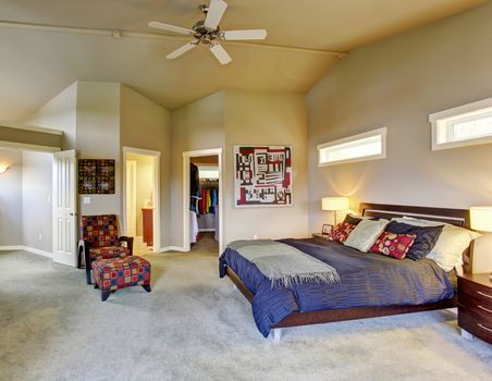 Large master bedroom with windows, fireplace,  colorful furniture, and connecting bathroom.