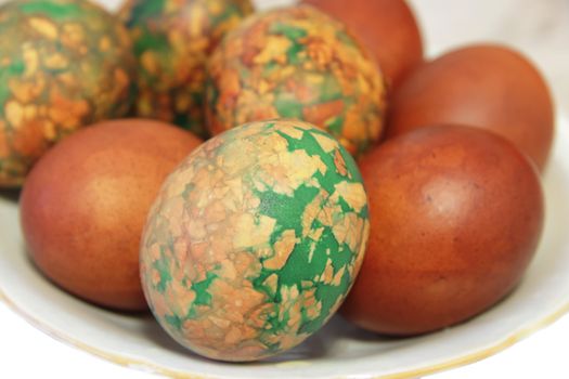 Colorful Easter eggs on white plate placed