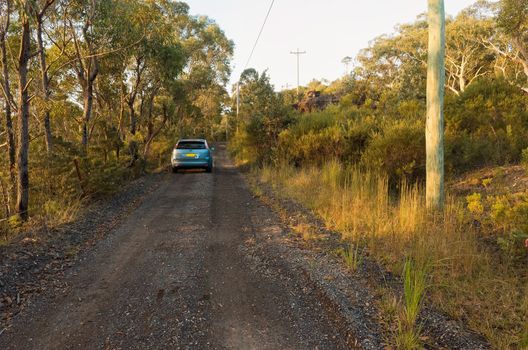 Photograph of an Australian dirt road with a parked car in the sunset