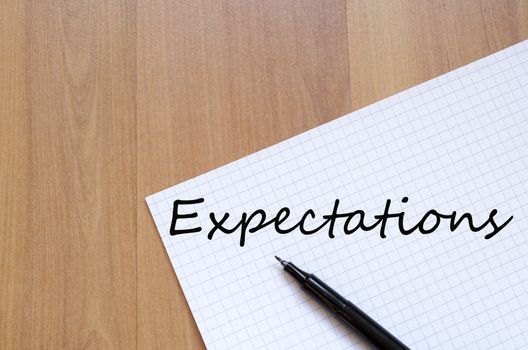 White blank notepad on office wooden table Expectations concept