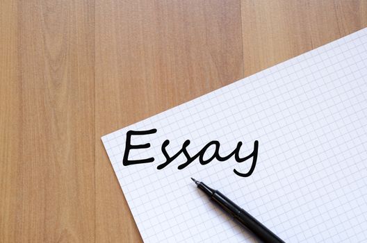 White blank notepad on office wooden table Essay concept
