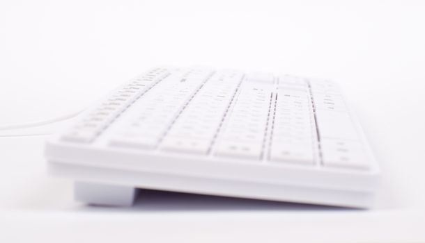 White keyboard with wire on isolated white background, side view