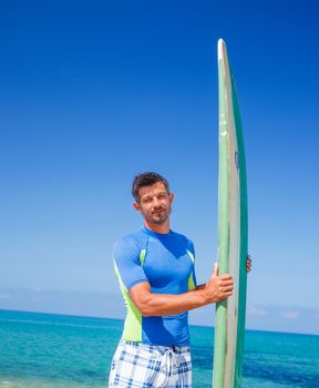 Strong young surf man at the beach with a surfboard.