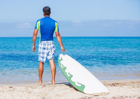 Strong young surf man at the beach with a surfboard.