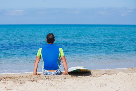 Strong young surf man at the beach with a surfboard.