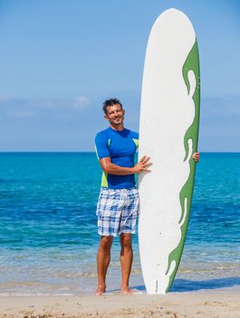 Strong young surf man at the beach with a surfboard.