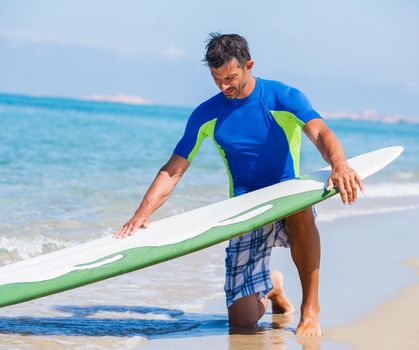 Strong young surf man at the beach with a surfboard.