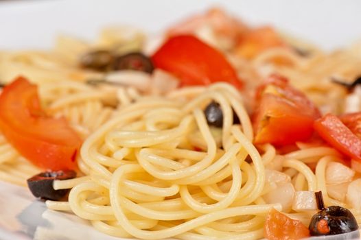 Pasta with tomato, black olives, capers and greens