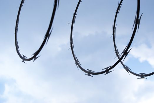 Photograph of a cloudy blue sky with a barb wire shadow or silhouette