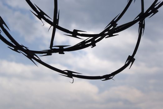Photograph of a cloudy blue bright sky with a barb wire silhouette