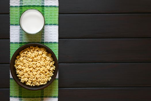 Honey flavored breakfast cereal in rustic bowl with a glass of milk, photographed overhead on dark wood with natural light 
