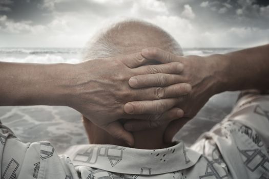 Senior man with hands behind his head looking at the sea