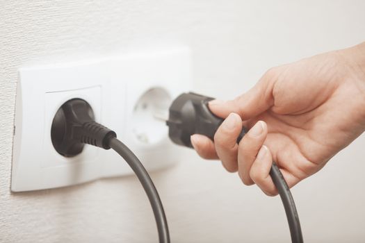 Woman pluging cable to the electric outlet