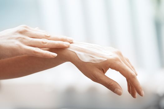 Woman applying moisturizing cream on hands