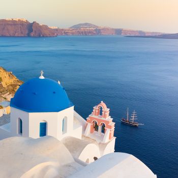 World famous traditional whitewashed chuches and houses of Oia village on Santorini island, Greece. Sunset light.