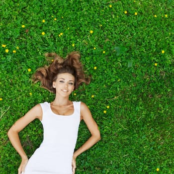 beautiful young woman in white dress lying on grass