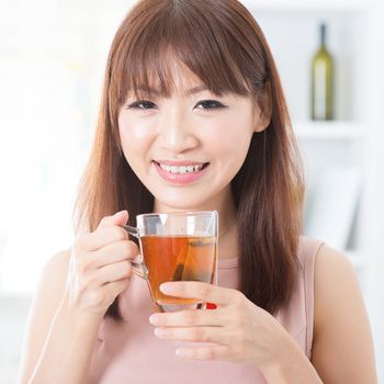 Portrait of attractive Asian girl enjoying cup of hot tea in the morning. Young woman indoors living lifestyle at home.