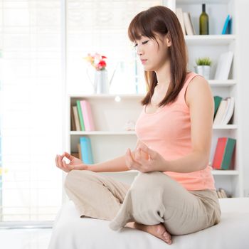 Portrait of calm Asian girl meditation in the morning. Young woman indoors living lifestyle at home.