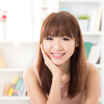 Portrait of Asian girl hand holding face, relaxed and smiling at home, woman living lifestyle indoors.