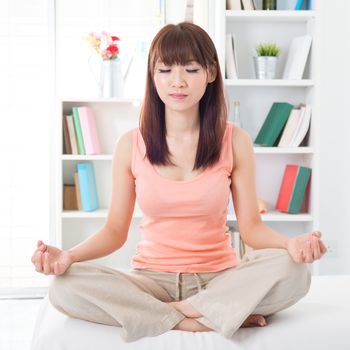 Portrait of calm Asian girl meditating in the morning. Young woman indoors living lifestyle at home.