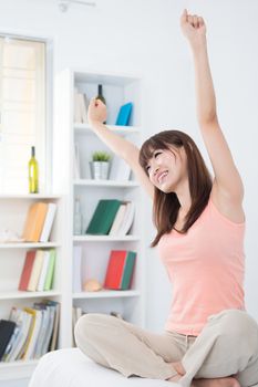 Portrait of Asian girl woke up and stretching arms in the morning. Young woman indoors living lifestyle at home.