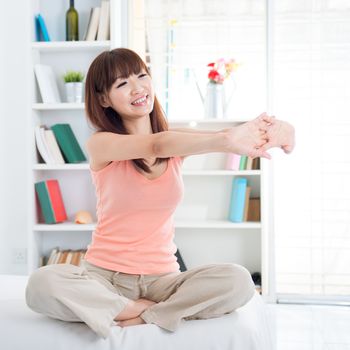 Portrait of Asian girl stretching arms in the morning on her bed. Young woman indoors living lifestyle at home.
