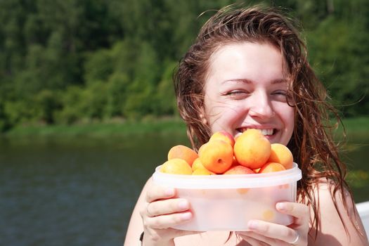 Closeup portrait of smiling beautiful teenage girl with apricots