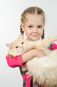 Portrait of cheerful four-year girl with cat in her arms