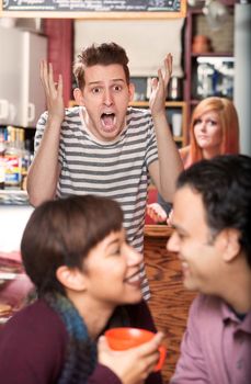 Screaming young man watching happy couple in cafe