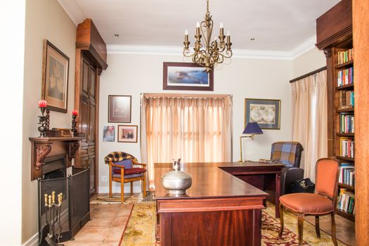 A private study in a residential home, complete with table and furniture, as well as a fire place.