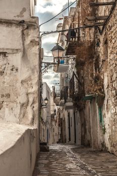 An old and narrow road laid with stone and pebbles lead in to the old town of Ibiza, flanked by old houses on both sides.