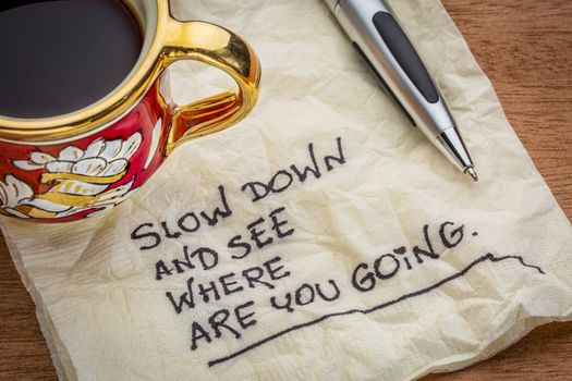 slow down and see where are you going - motivational reminder - handwriting on a napkin with a cup of coffee