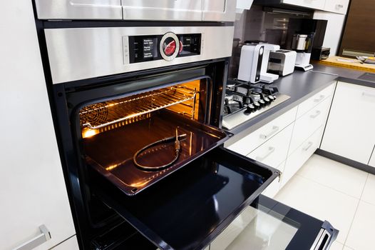 Modern luxury hi-tek black and white kitchen, clean interior design, focu at oven with door open