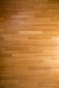 Background texture of a wooden bamboo floor with laminated floorboards, viewed overhead with side lighting and a gradient for an architectural or interior decor theme
