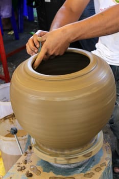 Hands of a potter making in clay on pottery wheel