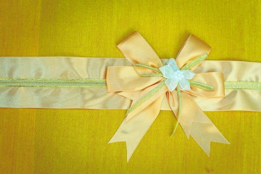 Abstract ribbon bow on fabric background.