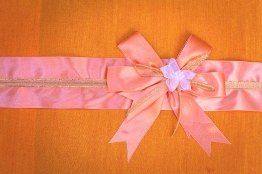 Abstract ribbon bow on fabric background.